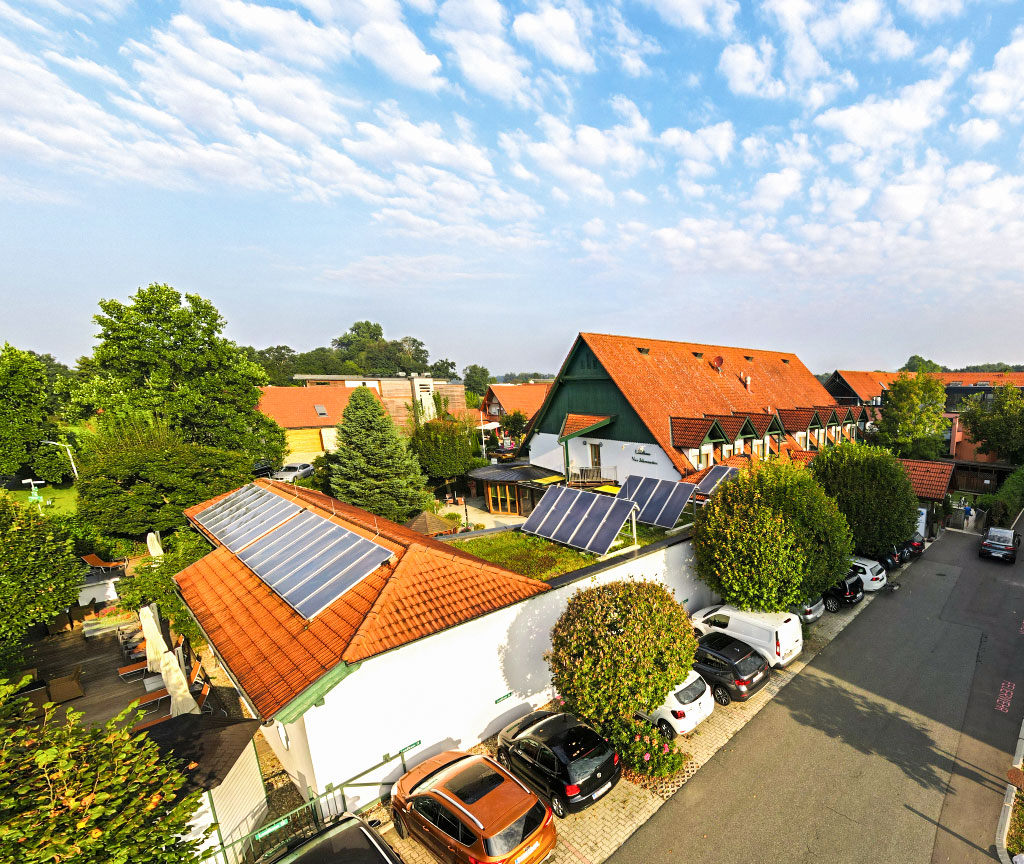 Drohnenbild Landhaus Vier Jahreszeiten bei blauem, leicht bewölkten Himmel mit Photovoltaik
